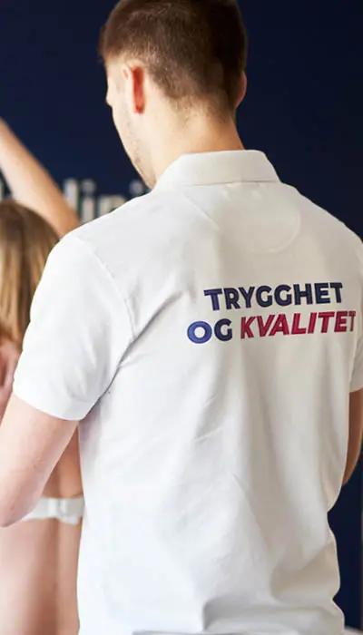 Mann som har på seg piqué med teksten "trygghet og kvalitet"