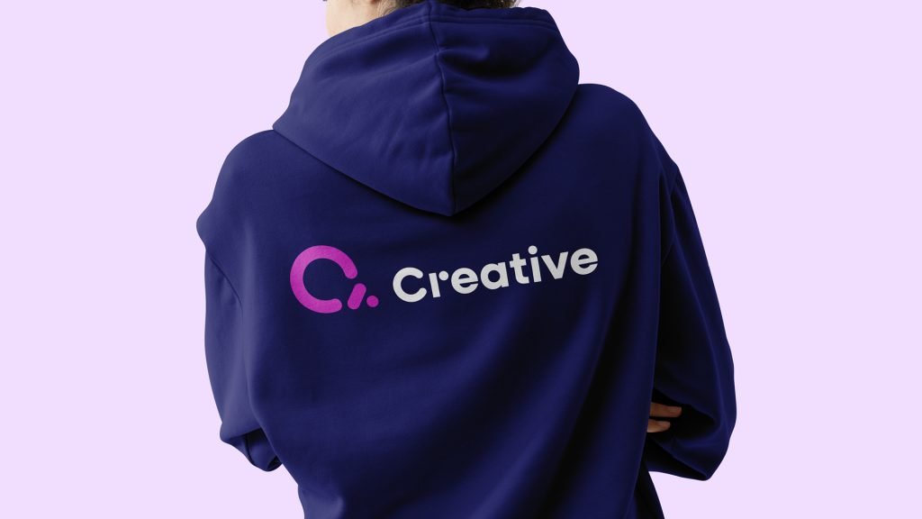 Person sett bakfra iført en mørk hoodie med den nye Creative-logoen på ryggen.
